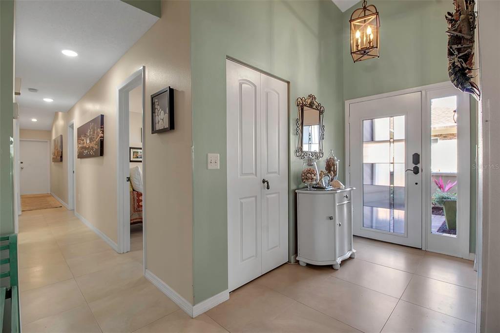 A bright entryway features light tile flooring, sage green walls, a white closet, and front doors — 3410 AVENIDA MADERA UNIT B, BRADENTON, FL