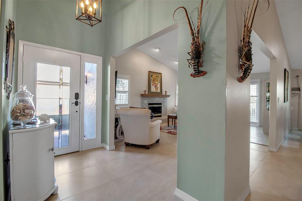 A bright entryway features light tile floors, a white front door, and two wall-mounted lobsters — 3410 AVENIDA MADERA UNIT B, BRADENTON, FL
