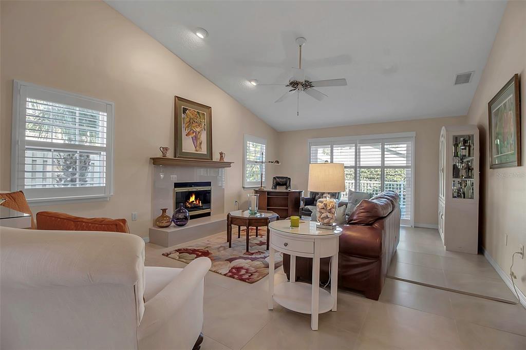 A living room features a fireplace, tile flooring, a ceiling fan, and a leather sofa — 3410 AVENIDA MADERA UNIT B, BRADENTON, FL