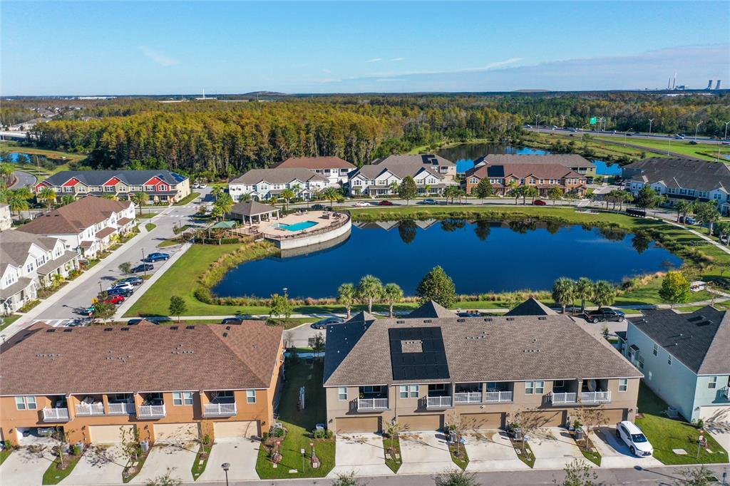 An aerial view shows townhomes surrounding a central pond with a community pool and clubhouse — 10251 HIGHLINE CREST STREET, ORLANDO, FL