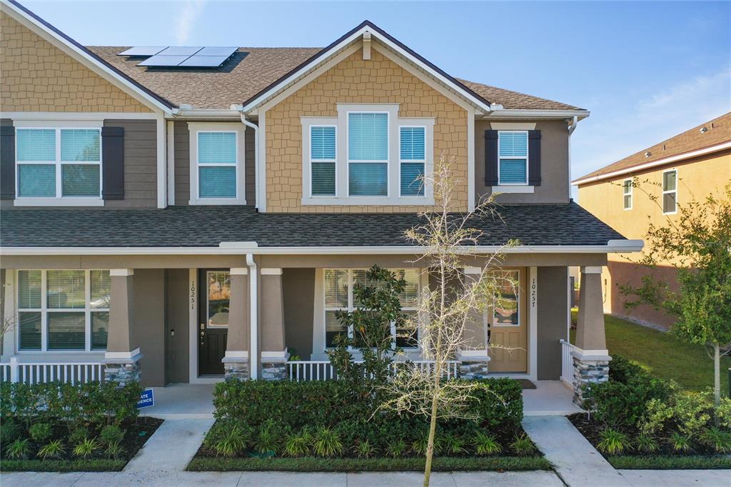 The exterior of a two-story townhouse features tan siding, stone accents, and a covered porch — 10251 HIGHLINE CREST STREET, ORLANDO, FL