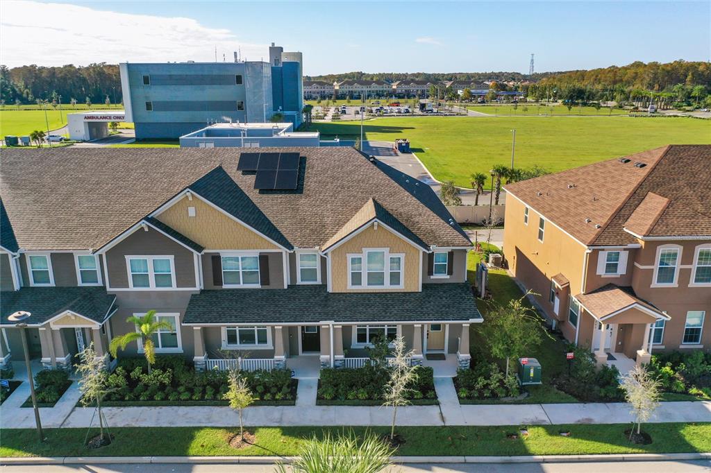 An exterior view of a multi-unit townhouse building with solar panels on the roof — 10251 HIGHLINE CREST STREET, ORLANDO, FL