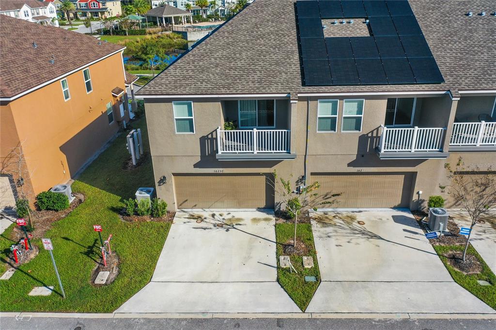 An aerial view shows two attached townhomes with tan stucco exteriors, balconies, and solar panels — 10251 HIGHLINE CREST STREET, ORLANDO, FL