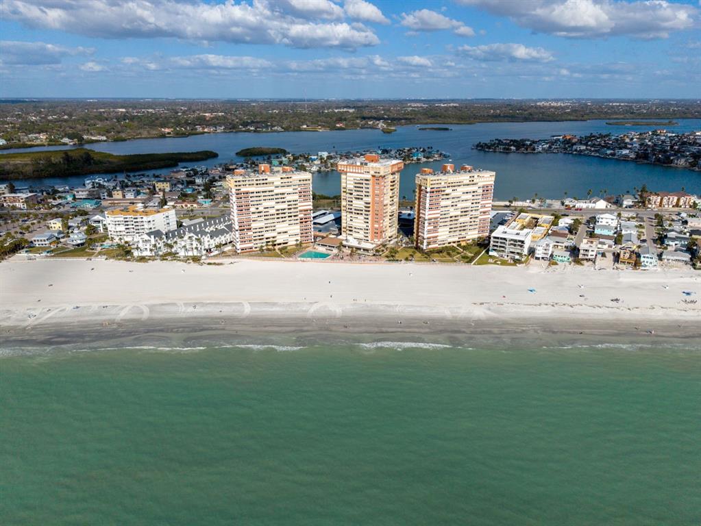 An aerial view shows three tall beachfront condominiums situated along a sandy coastline — 17900 GULF BOULEVARD UNIT 12A, REDINGTON SHORES, FL