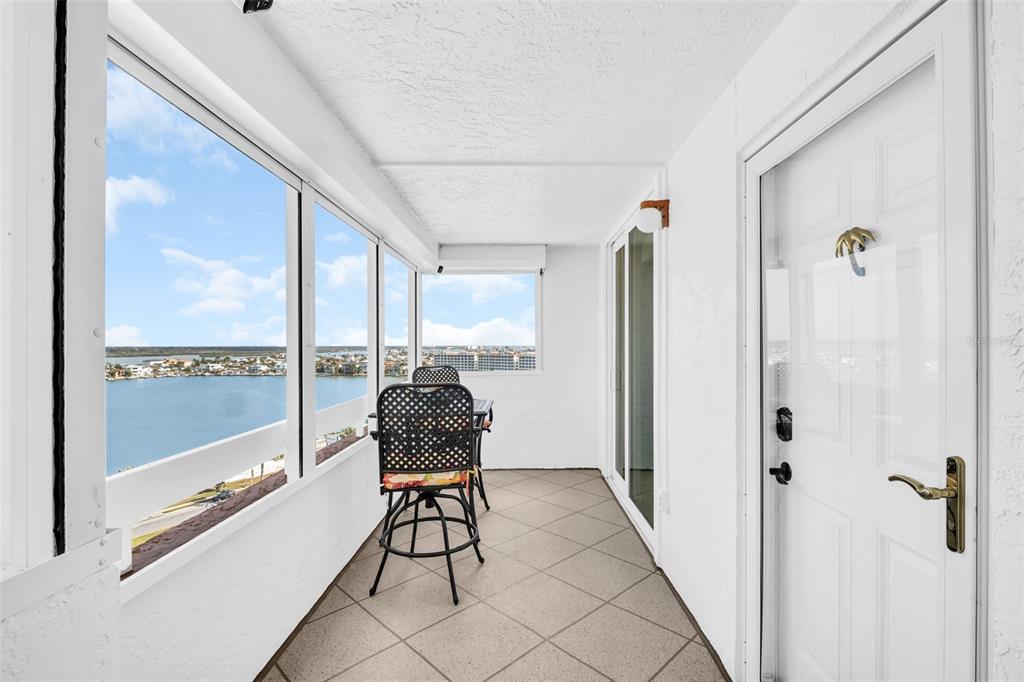 A sunroom with tile flooring, white walls, and large windows overlooking a waterfront view — 17900 GULF BOULEVARD UNIT 12A, REDINGTON SHORES, FL