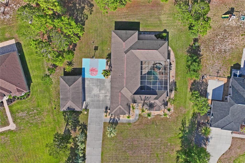 An aerial view shows a house with a pool enclosure, basketball court, and detached garage — 10120 SHORTLEAF COURT, WEEKI WACHEE, FL