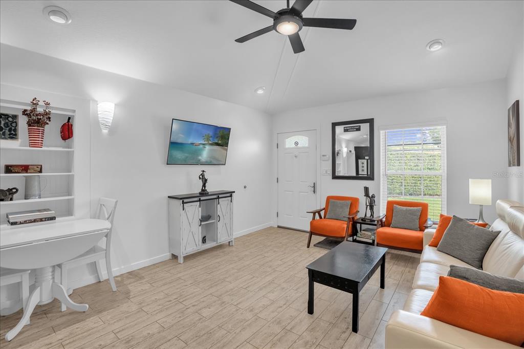 A living room features light wood-look tile flooring, a white sofa, and two orange chairs — 726/720 N PENNSYLVANIA AVENUE, WINTER PARK, FL
