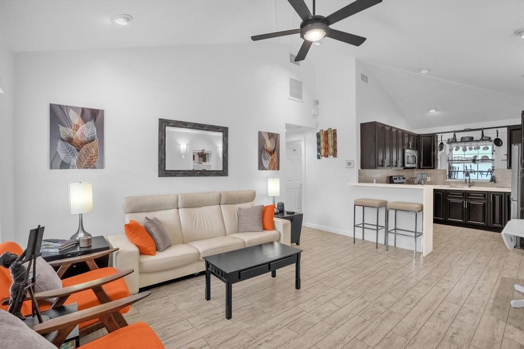 A living room with a beige sofa, orange chairs, and an open kitchen with dark cabinets — 726/720 N PENNSYLVANIA AVENUE, WINTER PARK, FL