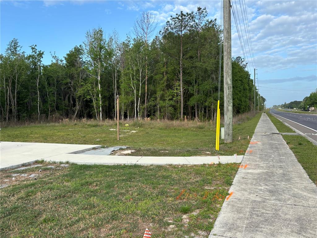 A vacant, grassy lot sits adjacent to a sidewalk and a paved road — SE HAWTHORNE ROAD, HAWTHORNE, FL
