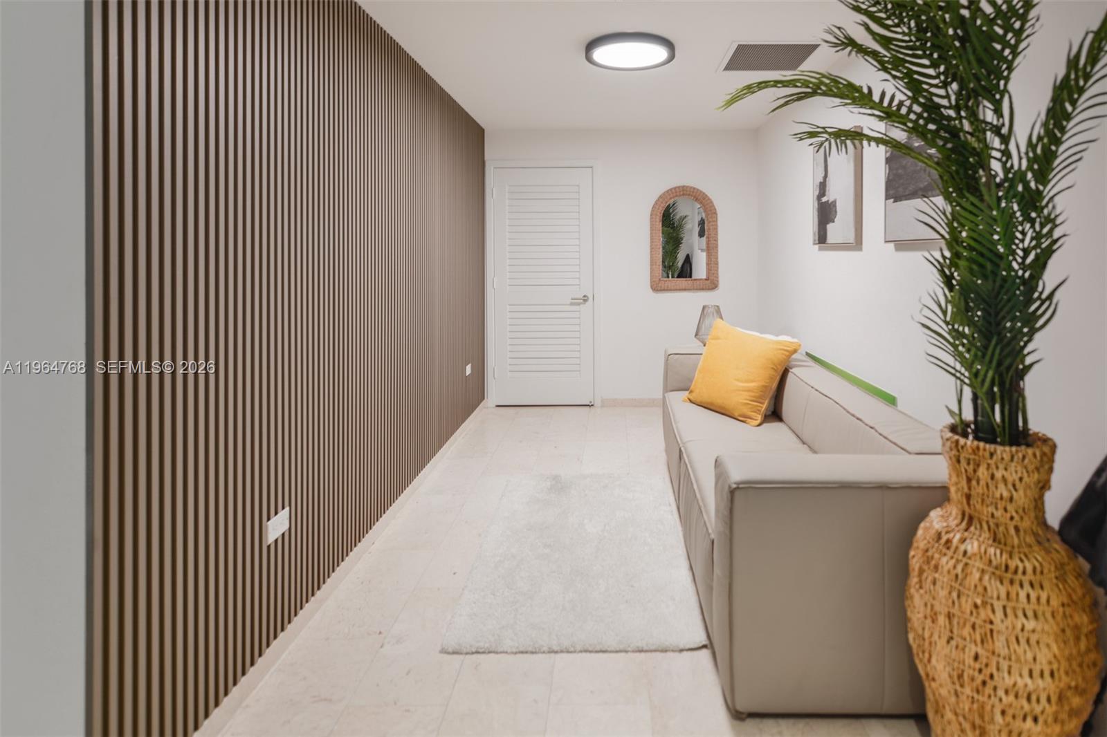 A room features a slatted wood accent wall, a beige sofa, and a potted plant — 88 SW 7th St # 2204, Miami FL 33130, MIAMI, FL