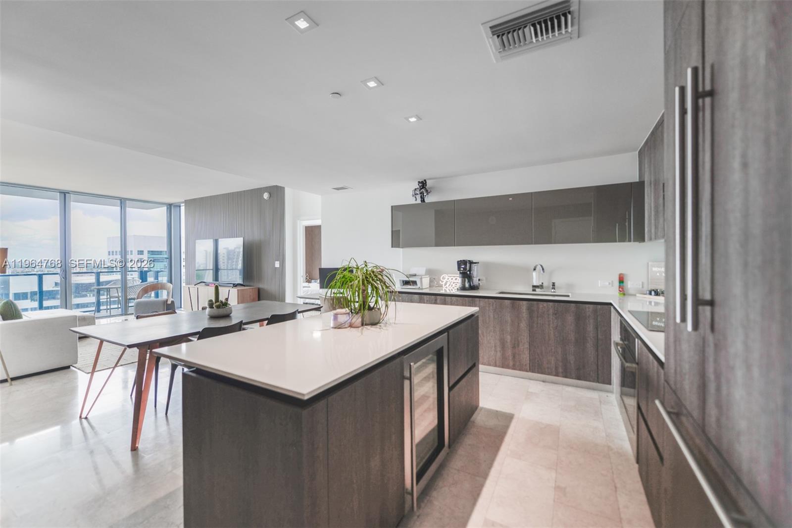 A modern kitchen features dark wood cabinetry, a white island, and an adjacent dining area — 88 SW 7th St # 2204, Miami FL 33130, MIAMI, FL