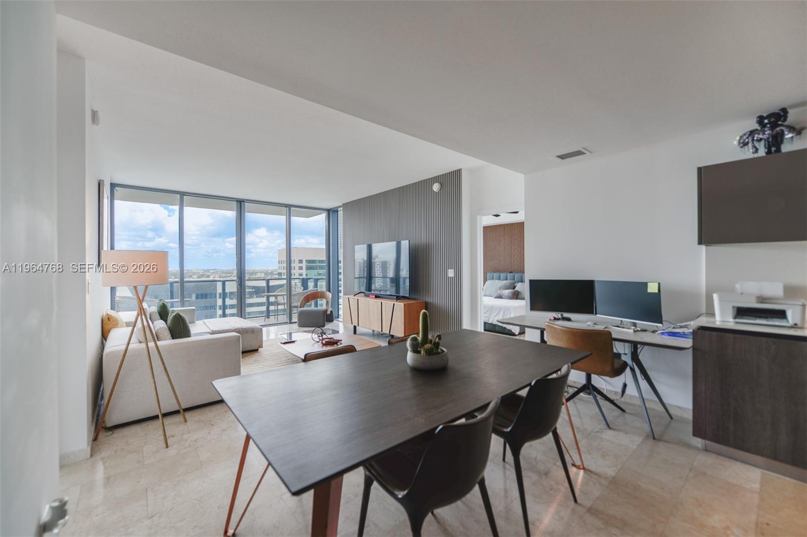 A modern open-concept living and dining area features floor-to-ceiling windows and a home office — 88 SW 7th St # 2204, Miami FL 33130, MIAMI, FL