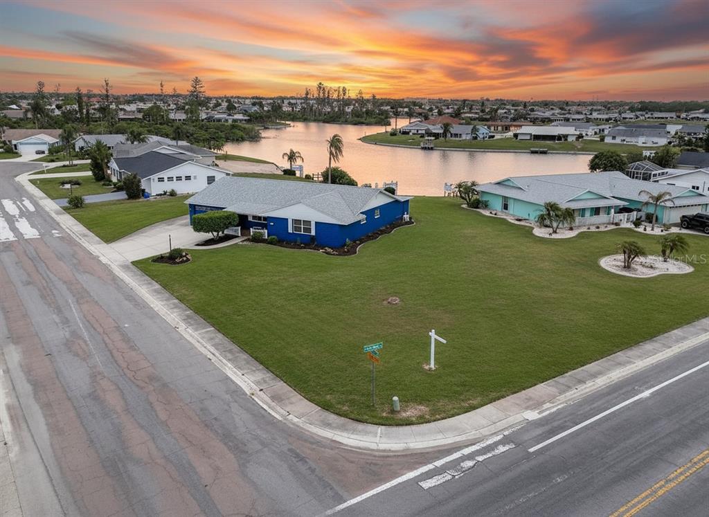 An aerial view shows a blue house on a corner lot next to a lake — 1810 MILFORD CIRCLE, SUN CITY CENTER, FL