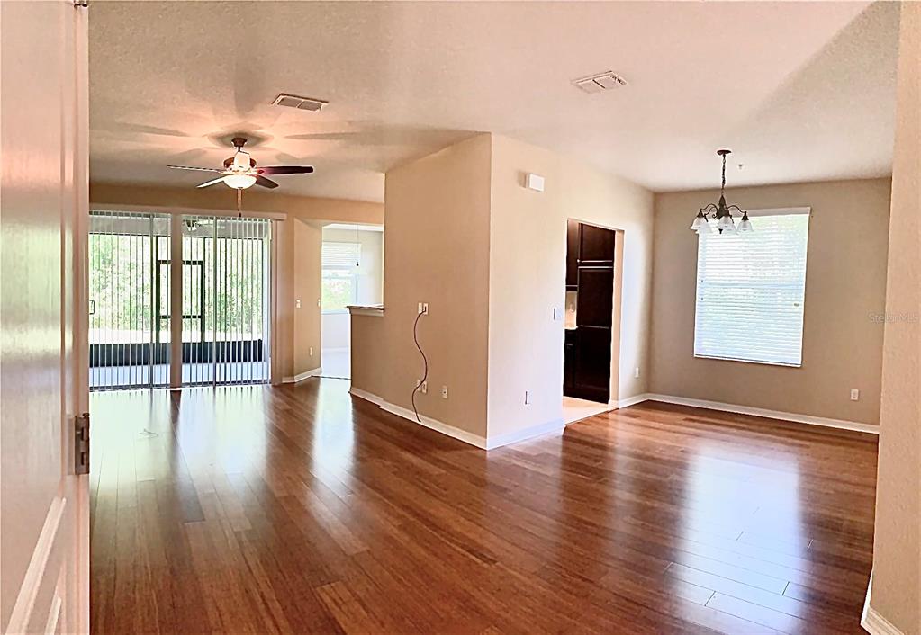 An open-concept living and dining area features hardwood floors, a ceiling fan, and sliding doors — 8363 BELLA TIERRA CT, DAVENPORT, FL