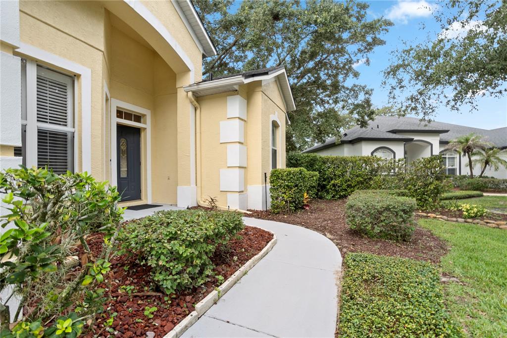 A yellow stucco house exterior features a front walkway leading to a dark entry door — 1393 STANFIELD COVE, LAKE MARY, FL