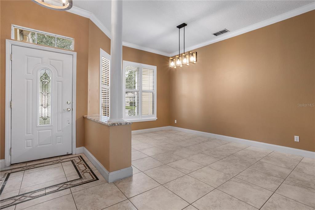 This dining area features tan walls, tile flooring, a white front door, and a chandelier — 1393 STANFIELD COVE, LAKE MARY, FL
