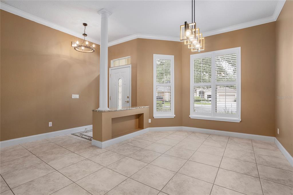A dining room features tan walls, tile flooring, a granite-topped pony wall, and two chandeliers — 1393 STANFIELD COVE, LAKE MARY, FL