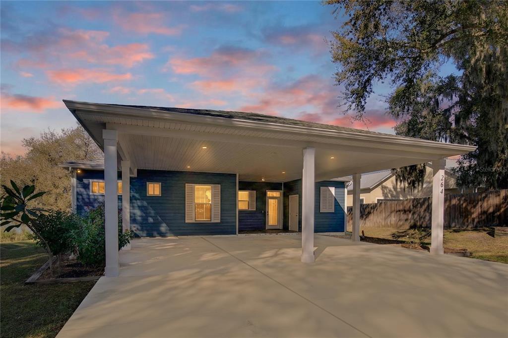 A blue house with a large concrete carport and white support columns at dusk — 264 S CENTRAL AVENUE, UMATILLA, FL