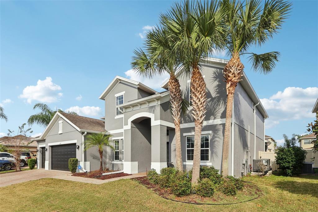 A two-story gray house with a dark garage, white trim, and palm trees in front — 2132 PLANTATION OAK DR, ORLANDO, FL