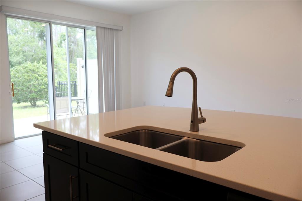 A kitchen island with a double-basin sink and faucet sits before a sliding glass door — 3635 DAVENPORT CREEK COURT, KISSIMMEE, FL