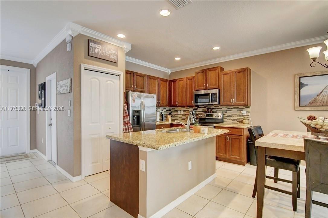 A kitchen features wood cabinets, granite countertops, a center island, and tile flooring — 1071 NW 33rd Ct, Pompano Beach FL 33064, POMPANO BEACH, FL