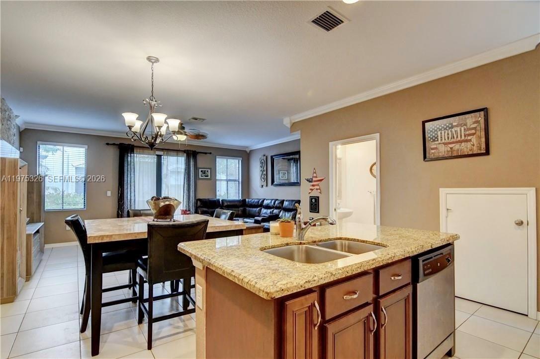 A kitchen island with granite countertops overlooks a dining area and living room — 1071 NW 33rd Ct, Pompano Beach FL 33064, POMPANO BEACH, FL