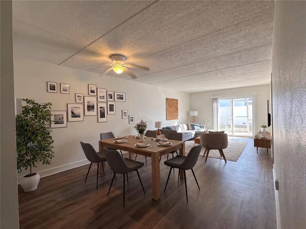 A dining area with a wooden table and chairs opens into a living room with furniture — 4435 1ST STREET NE UNIT 103, ST PETERSBURG, FL