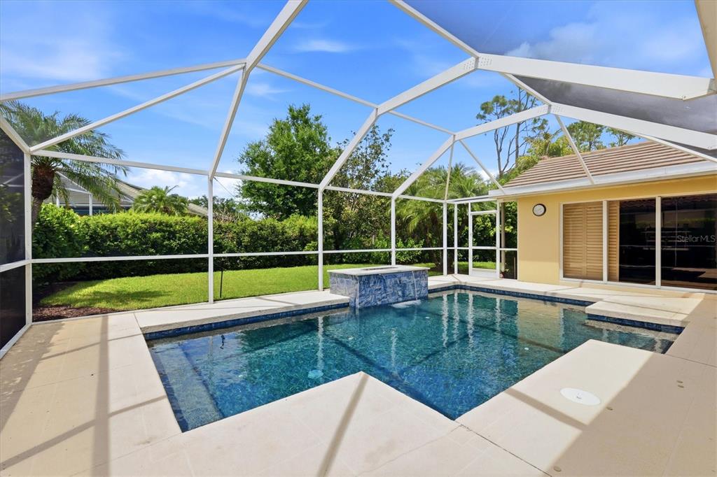 A living room with a sectional sofa and two patterned chairs opens to a kitchen — 8412 MISTY MORNING COURT, LAKEWOOD RANCH, FL
