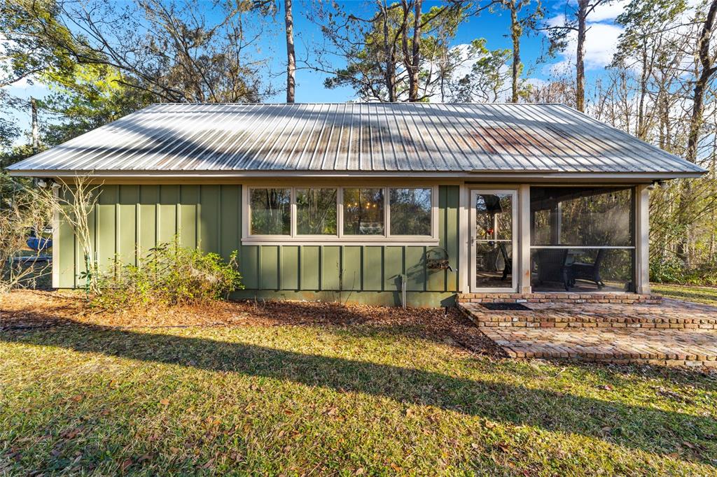 A green, single-story house with a metal roof, large windows, and a screened-in porch — 10801 SW 185TH TERRACE, DUNNELLON, FL