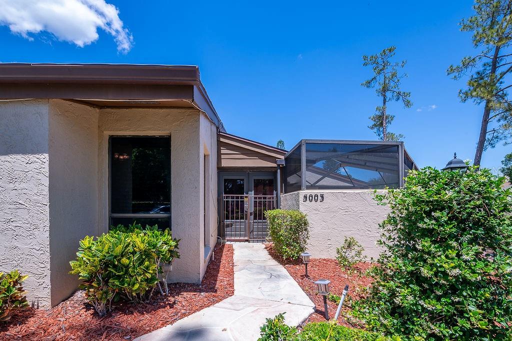 A stone walkway leads to the front entrance of a house with a screened enclosure — 5003 UMBER WAY S, TAMPA, FL
