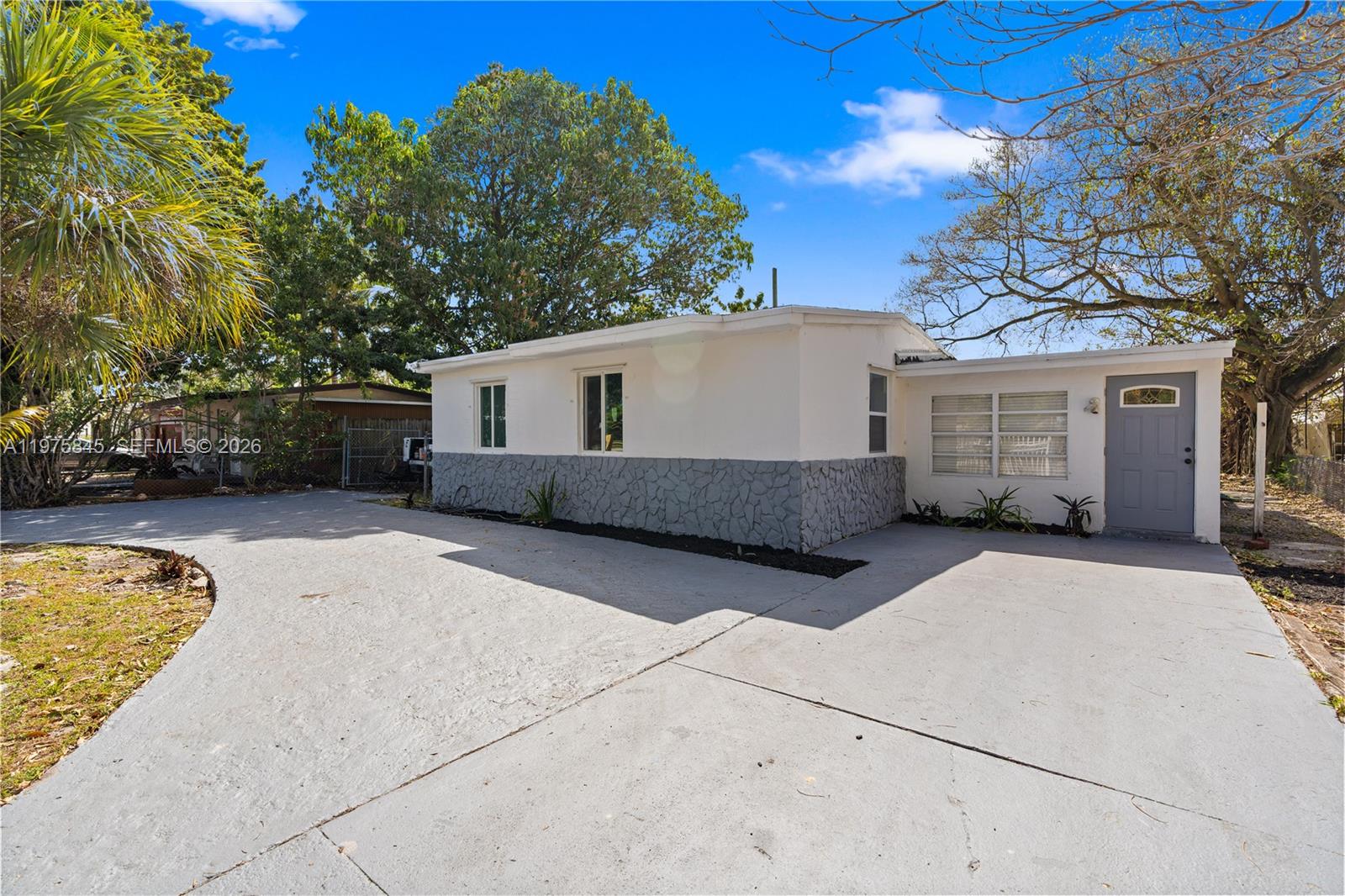 A white single-story house with a gray stone base and a concrete driveway — 4520 SW 38th St, West Park FL 33023, WEST PARK, FL