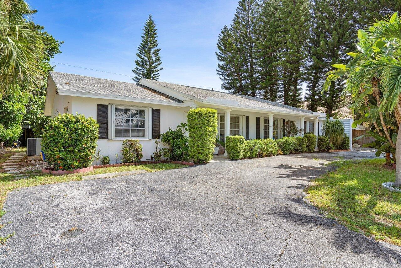 A single-story white house with a cracked asphalt driveway and surrounding landscaping — 13 Sailfish Lane, Ocean Ridge FL 33435, OCEAN RIDGE, FL