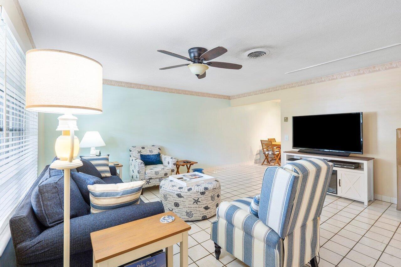 A living room features a blue sofa, striped armchair, patterned ottoman, and a television console — 13 Sailfish Lane, Ocean Ridge FL 33435, OCEAN RIDGE, FL