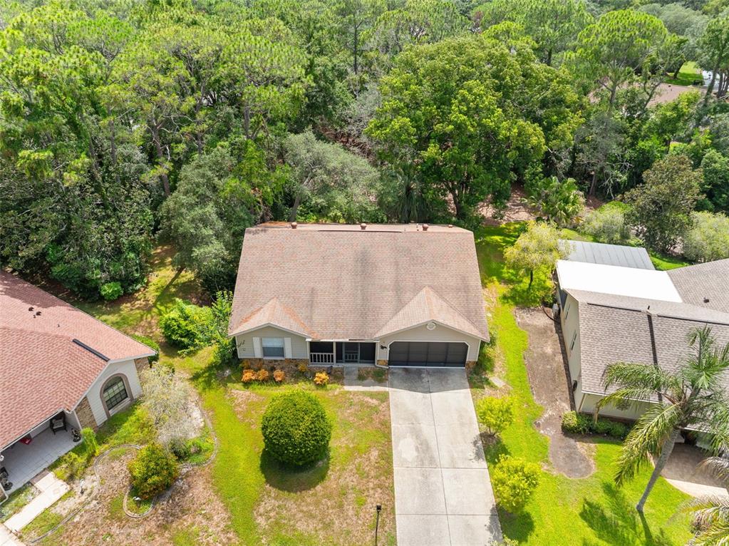 An aerial view shows a single-story house with a shingled roof and a concrete driveway — 2629 IMPERIAL PINE DRIVE, SPRING HILL, FL