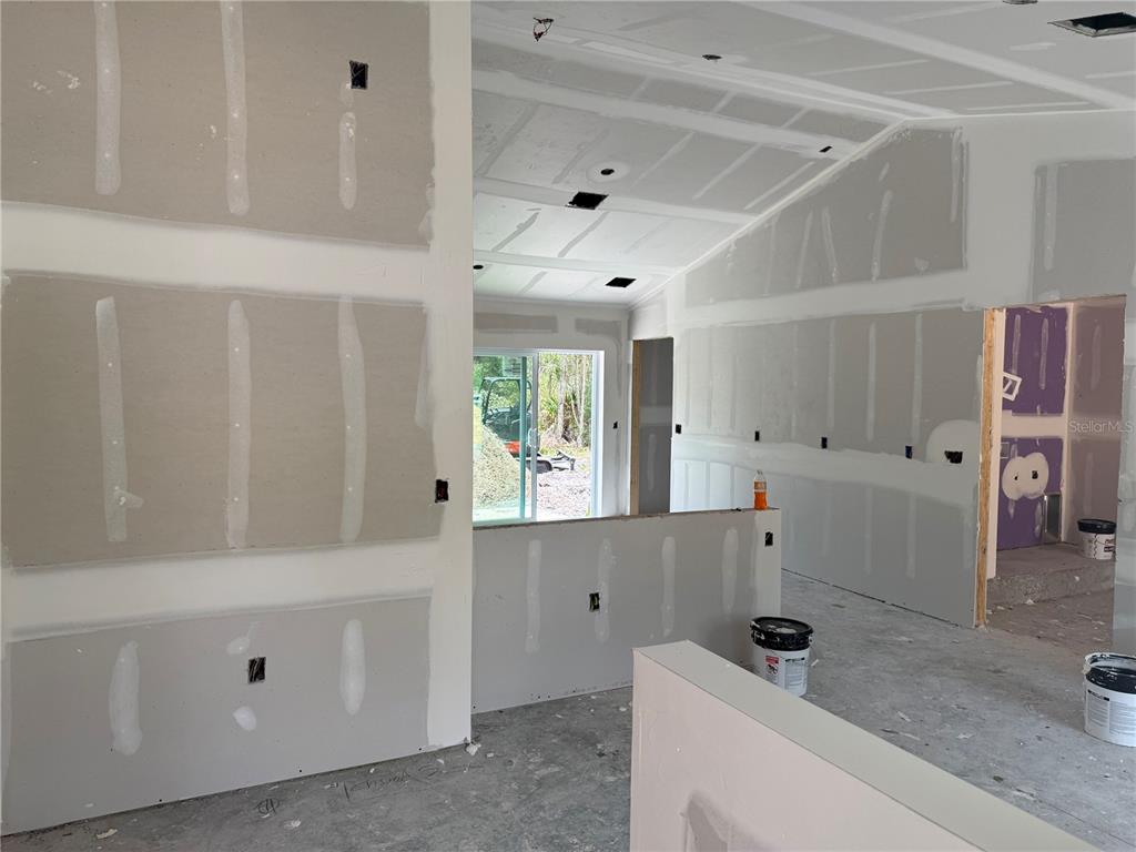 An interior view of a room under construction with unfinished drywall, exposed electrical boxes, and flooring — 12227 MARYLAND AVENUE, PUNTA GORDA, FL