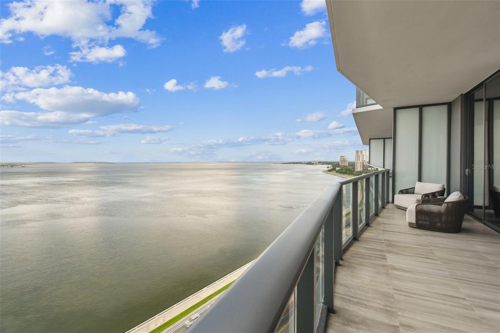A high-rise balcony with wood-look tile flooring overlooks a large body of water — 3101 BAYSHORE BOULEVARD UNIT 1402, TAMPA, FL