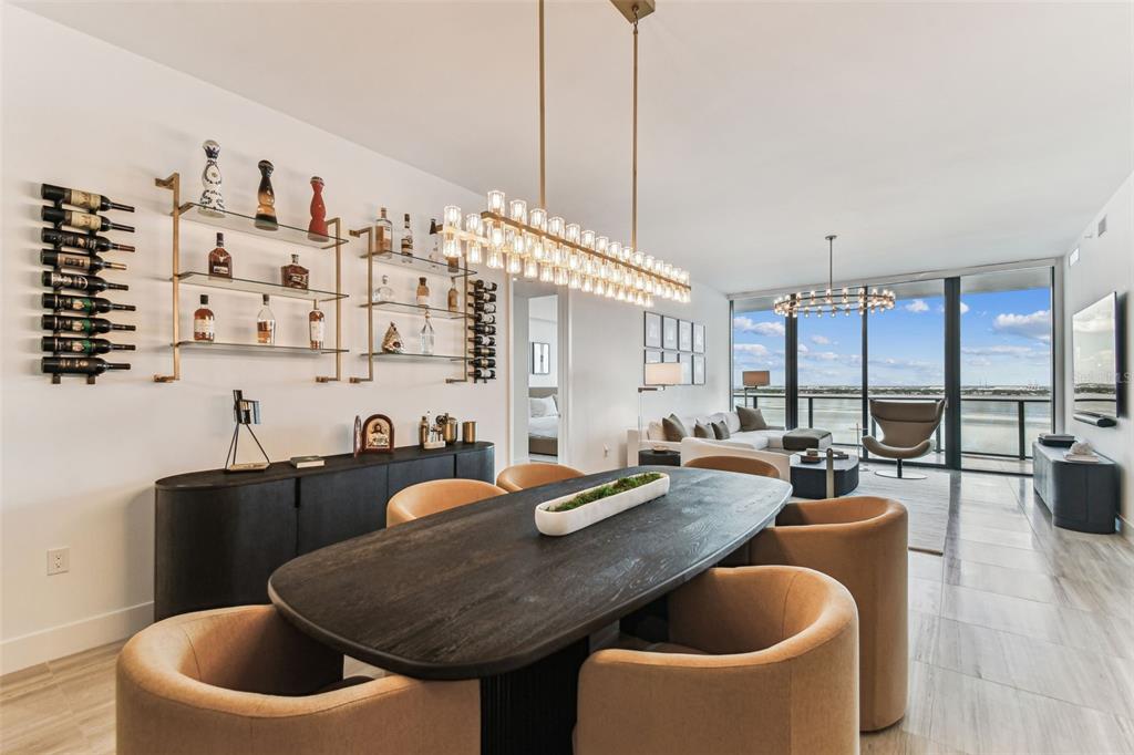 A modern dining room features a dark oval table, upholstered chairs, and a wall-mounted bar — 3101 BAYSHORE BOULEVARD UNIT 1402, TAMPA, FL