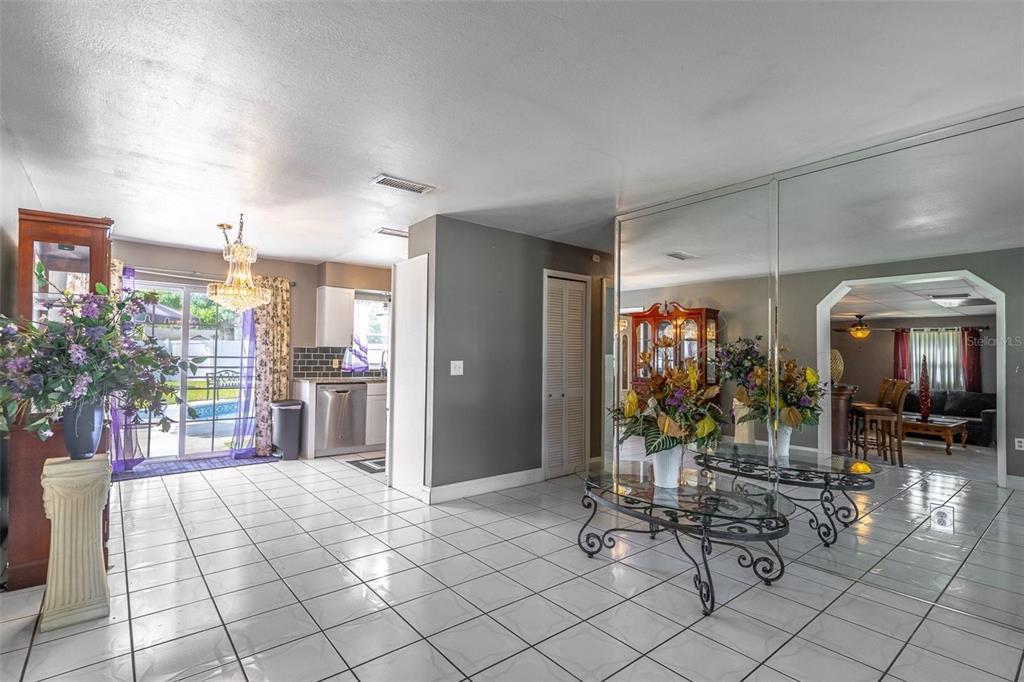 A tiled dining area features a mirrored wall, a chandelier, and an adjacent kitchen — 3226 KELVINGTON DRIVE, ORLANDO, FL
