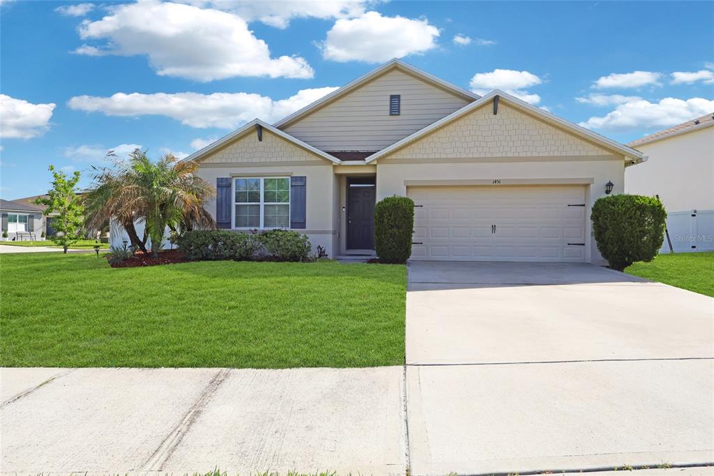 A single-story suburban house with a beige stucco facade, a two-car garage, and a lawn — 1451 TAOS AVENUE, KISSIMMEE, FL