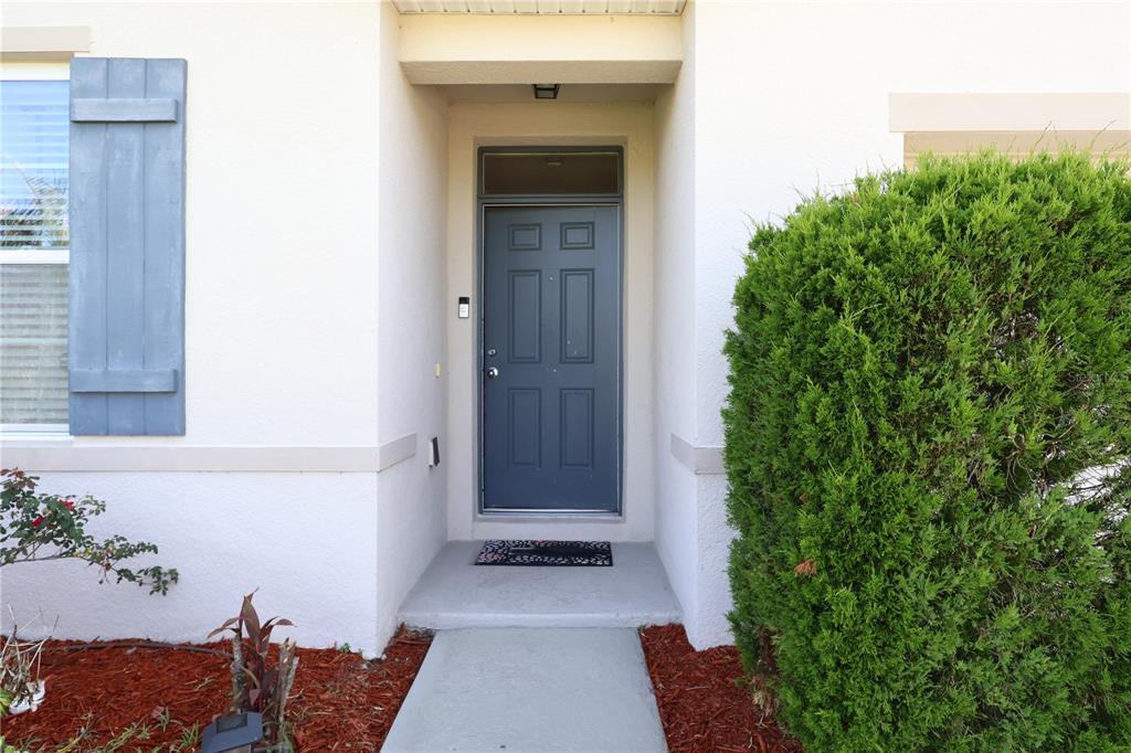 The exterior view shows a front door with a transom window and a nearby bush — 1451 TAOS AVENUE, KISSIMMEE, FL