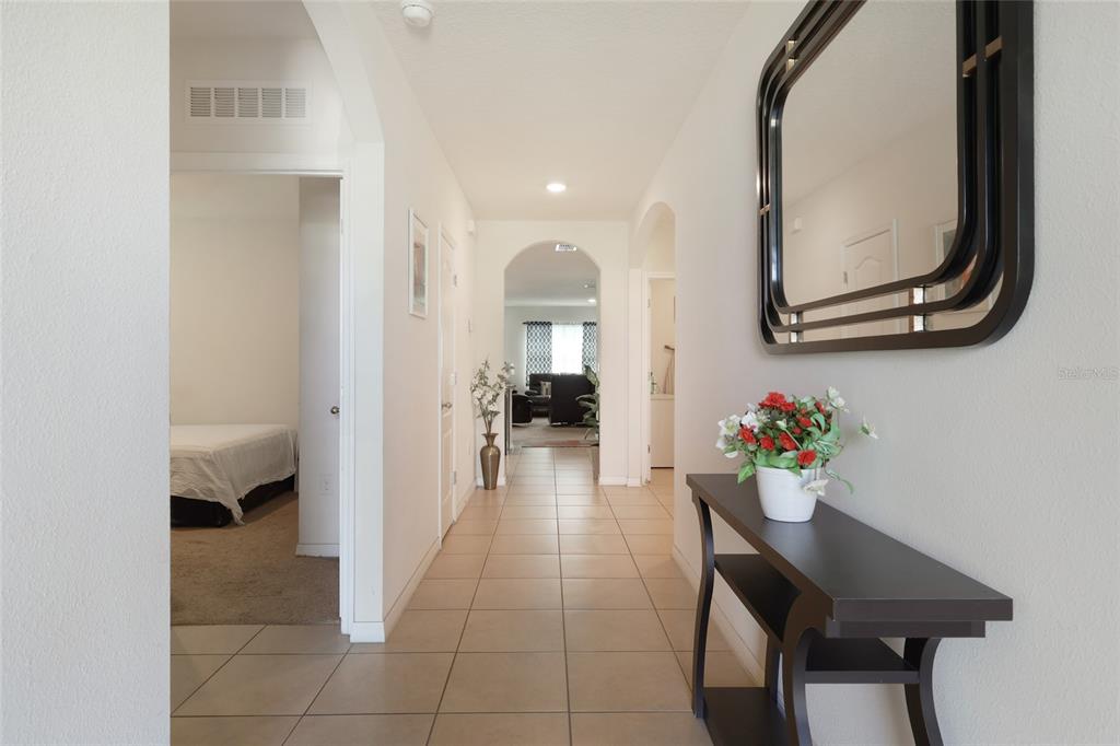 A tiled hallway features a console table with a mirror and leads to a living area — 1451 TAOS AVENUE, KISSIMMEE, FL