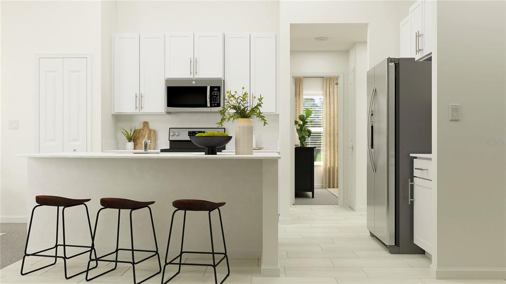 A modern kitchen features white cabinets, stainless steel appliances, a breakfast bar, and three stools — 12405 PARSONS ISLE TERRACE, PALMETTO, FL