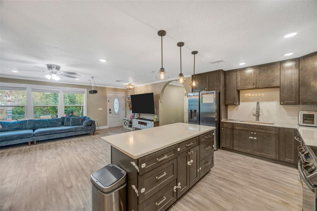 An open-concept kitchen with a central island overlooks a living area with a blue sofa — 7149 SPRUCE DRIVE, WEEKI WACHEE, FL