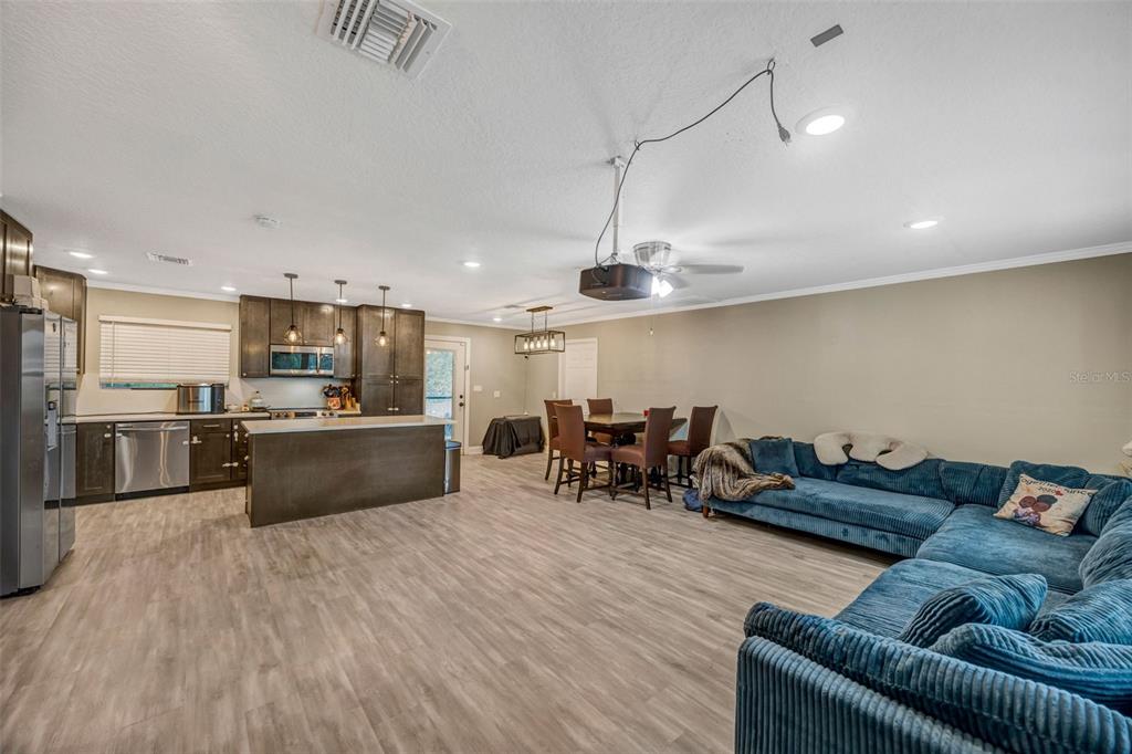 An open-concept living area features a kitchen with dark cabinets, a dining set, and sofa — 7149 SPRUCE DRIVE, WEEKI WACHEE, FL