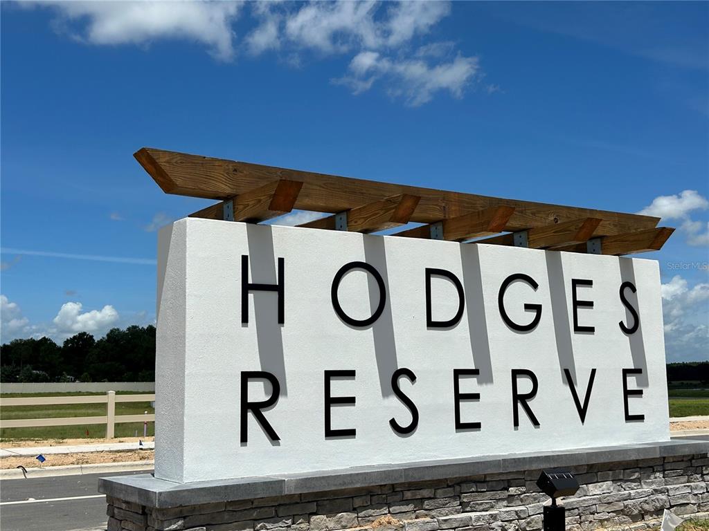 A white monument sign with black lettering reads Hodges Reserve under a wooden pergola structure — 24043 MORTIMER WAY, HOWEY IN THE HILLS, FL