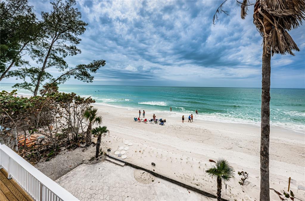 An elevated view of a sandy beach with people, palm trees, and the ocean — 8432 W GULF BOULEVARD UNIT Sailfish, TREASURE ISLAND, FL