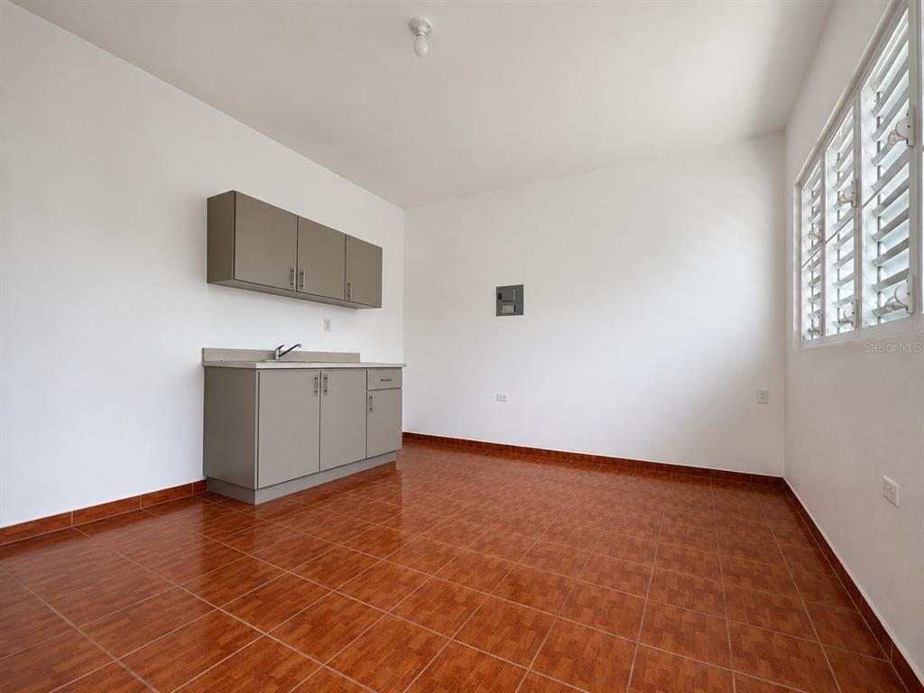 A small kitchen area features gray cabinets, a sink, and brown tiled flooring — CARR. 908 KM 9.4 BO. TEJAS APT. UNIT 7, HUMACAO, PR