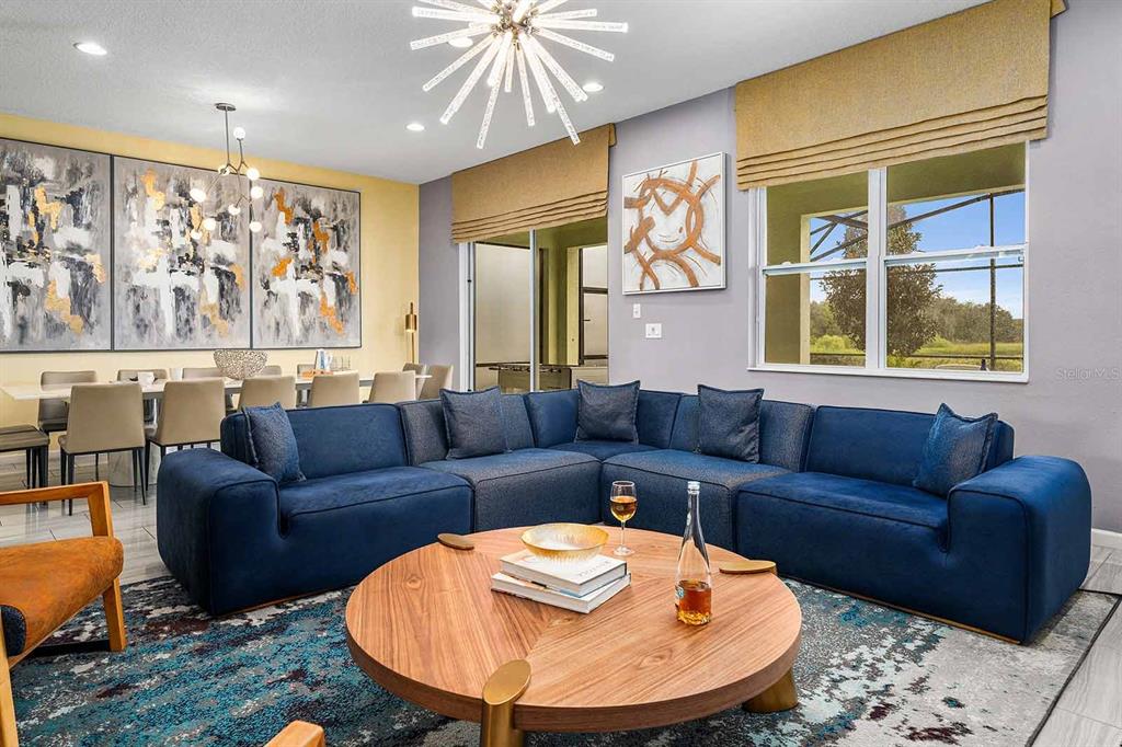 A living room features a large blue sectional sofa, a round wooden coffee table, and artwork — 8013 OAK SHADOW COURT, DAVENPORT, FL