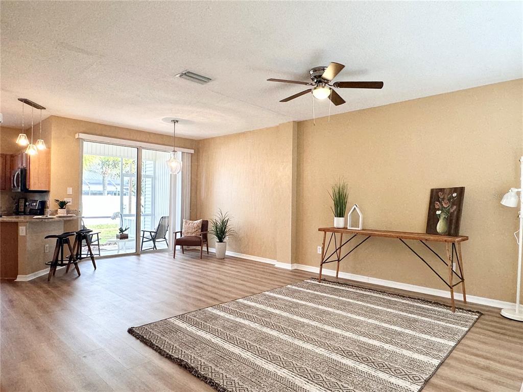 A living room features wood-look flooring, a ceiling fan, and a sliding glass door — 12276 COUNTRY WHITE CIRCLE, TAMPA, FL