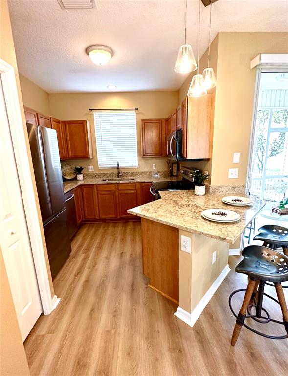 A kitchen features wood cabinets, granite countertops, stainless steel appliances, and a breakfast bar — 12276 COUNTRY WHITE CIRCLE, TAMPA, FL